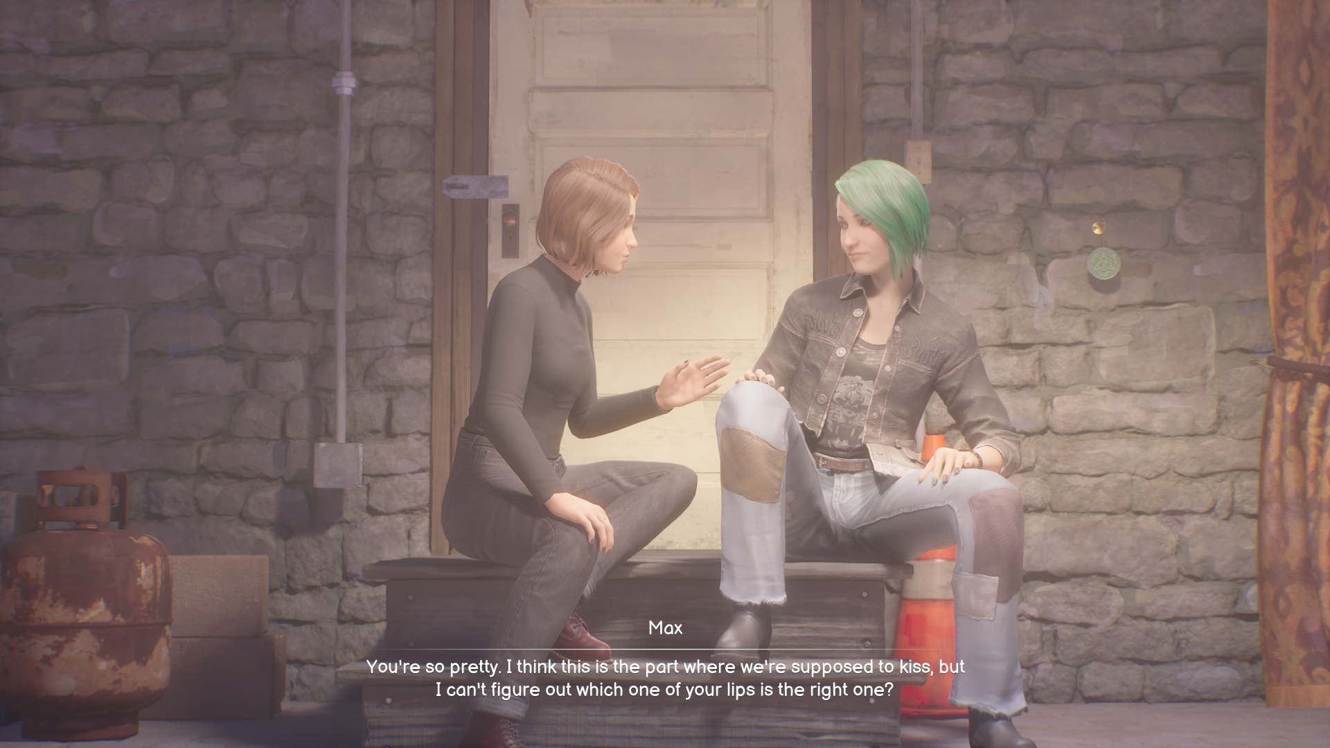 Two women sit on a wooden bench outside a stone building, one with short brown hair and a black top, the other with green hair and a denim jacket, gesturing while talking (subtitles shown).